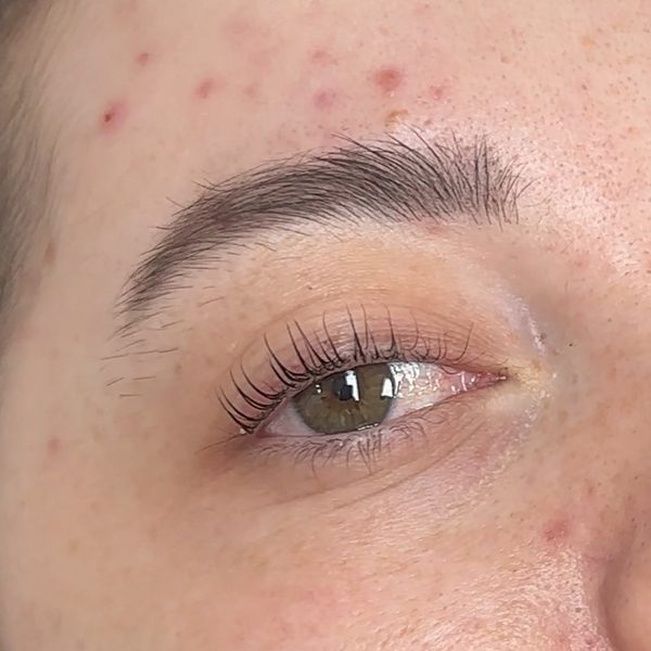 Close-up of one eye after a Korean lash lift: the natural lashes lifted and curled upward from the root, with a soft untinted brow above.