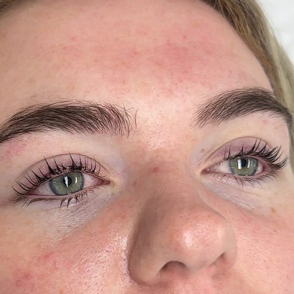 Both eyes after a Korean lash lift on a fair, freckled client: natural lashes lifted into an open curl, brows left soft and natural.