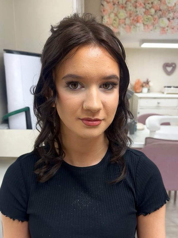 Prom make-up on a client with dark curled hair worn half-up: soft smoky eyes, flushed cheeks and a deep berry lip.