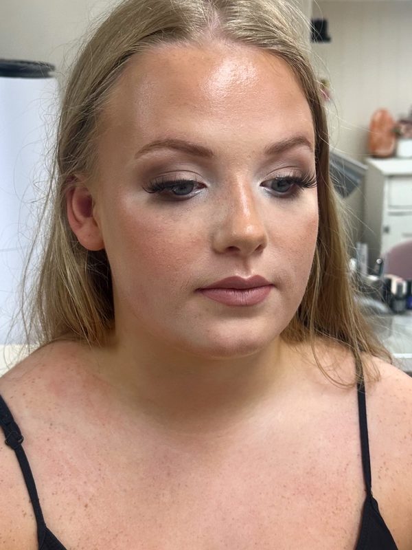 Prom make-up on a blonde client with her hair pulled back: smoky grey-taupe eyeshadow, strip lashes, strong cheekbone highlight and a glossy nude lip.