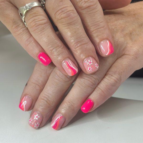 Short square builder gel nails in bright pink with nude accent nails hand-painted with white daisies and pink swirls.